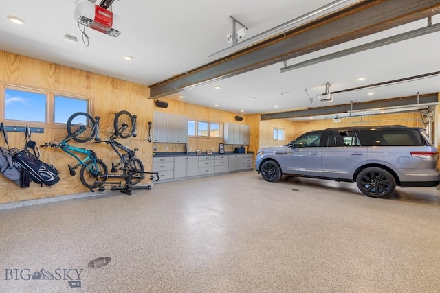 garage featuring recessed lighting, wood walls, and a garage door opener