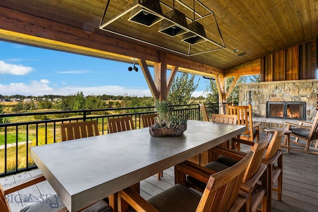 wooden terrace with outdoor dining space and an outdoor stone fireplace