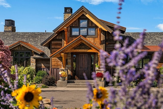 view of exterior entry featuring stone siding and a chimney