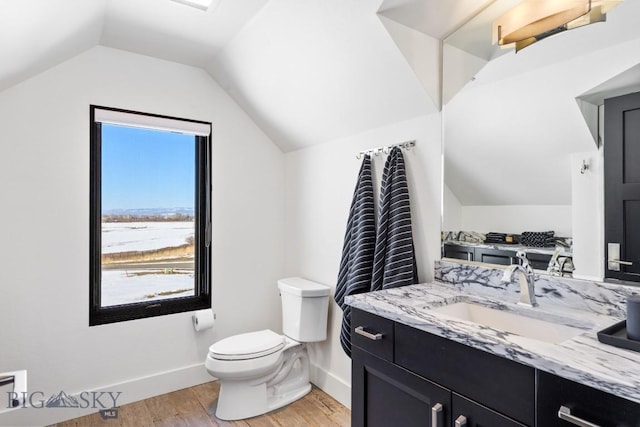 bathroom featuring toilet, wood finished floors, baseboards, vanity, and vaulted ceiling