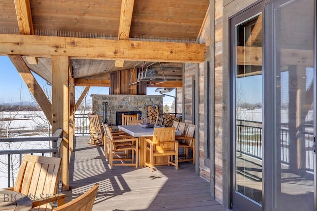 wooden terrace featuring an outdoor stone fireplace and outdoor dining space