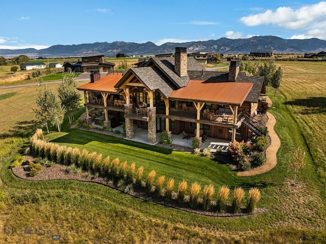 1468 Black Bull Trl, Bozeman, MT 59718 - back of house featuring a chimney, a patio, a yard, a mountain view, and metal roof