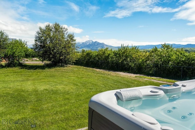 view of yard with a mountain view, a hot tub, and fence