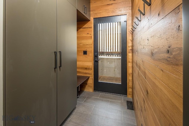 doorway to outside featuring visible vents and wooden walls