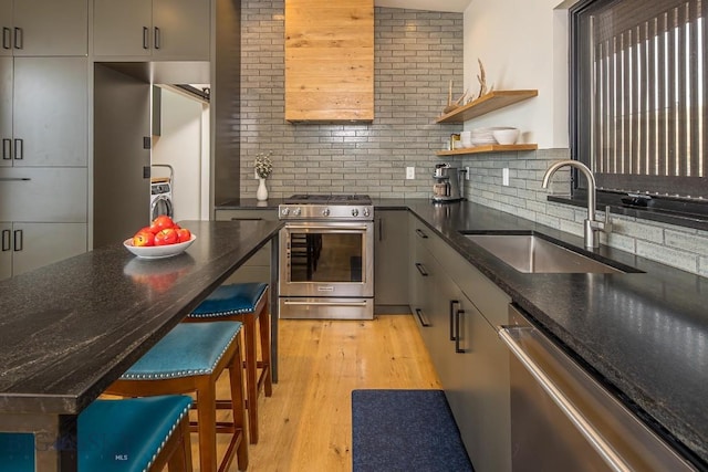 kitchen featuring backsplash, light wood-style flooring, stainless steel appliances, and a sink