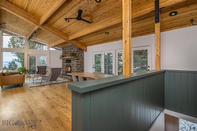 kitchen featuring beam ceiling, plenty of natural light, a stone fireplace, hardwood / wood-style flooring, and wood ceiling