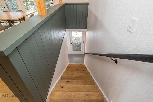 staircase featuring wood finished floors, baseboards, and a textured wall