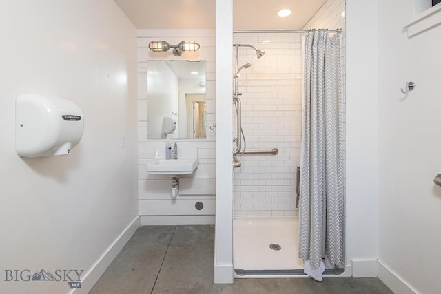 full bath with baseboards, a stall shower, and a sink