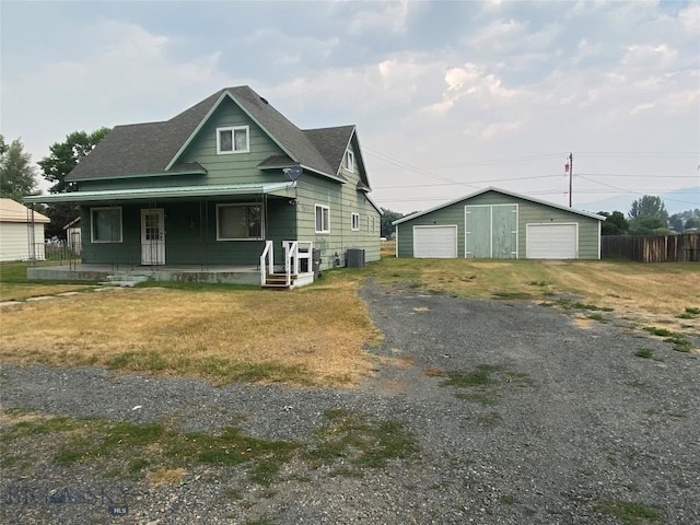 view of front of home with fence, covered porch, cooling unit, a garage, and an outbuilding