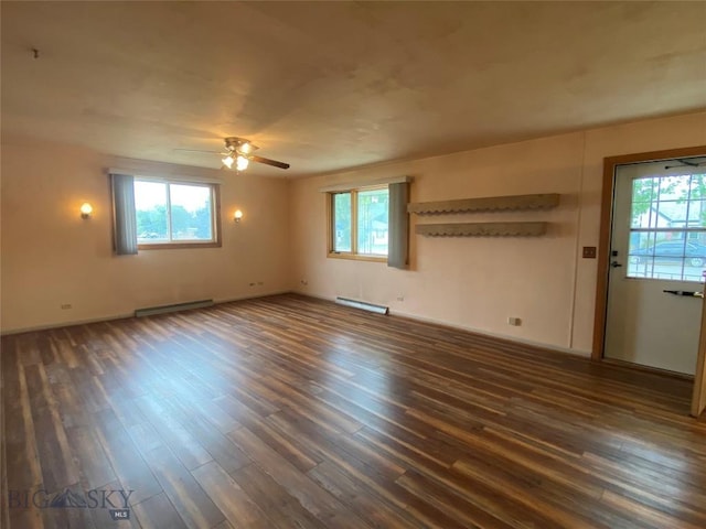 empty room featuring dark wood-style floors, a wealth of natural light, and a baseboard radiator