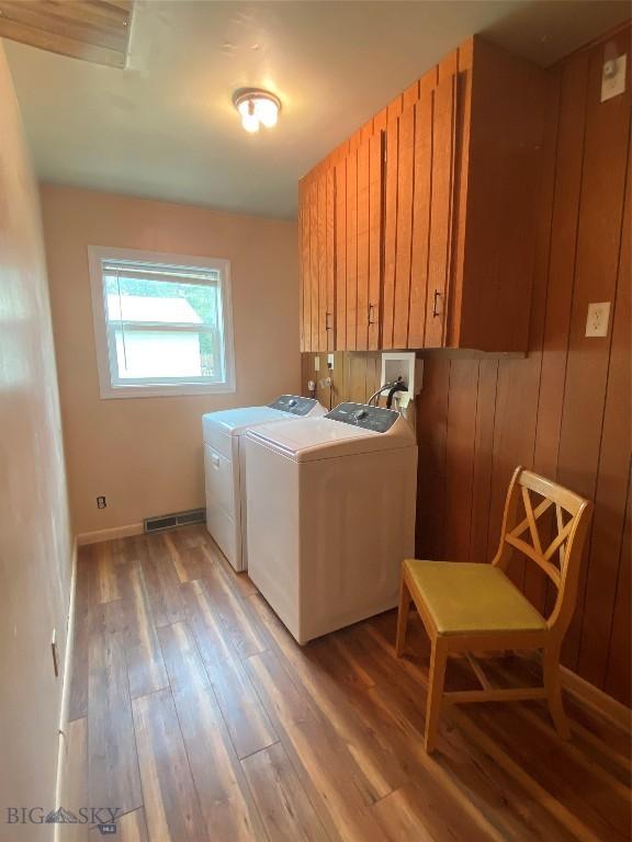 209 2nd St E, Whitehall, MT 59759 - washroom with washer and clothes dryer, cabinet space, light wood-style flooring, and baseboards