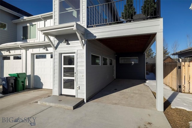 doorway to property featuring a balcony, a garage, and fence