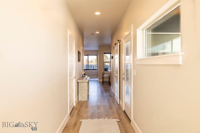 hall with recessed lighting, a barn door, baseboards, and wood finished floors