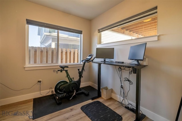 exercise room with baseboards and light wood finished floors