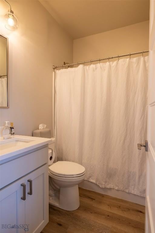 full bathroom featuring shower / bathtub combination with curtain, toilet, wood finished floors, and vanity