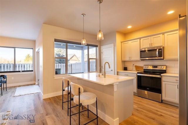 kitchen with backsplash, light wood-type flooring, light countertops, stainless steel appliances, and a sink