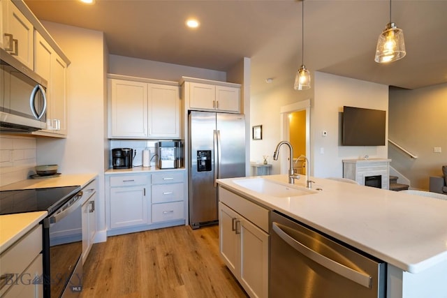 kitchen featuring pendant lighting, light countertops, decorative backsplash, stainless steel appliances, and a sink