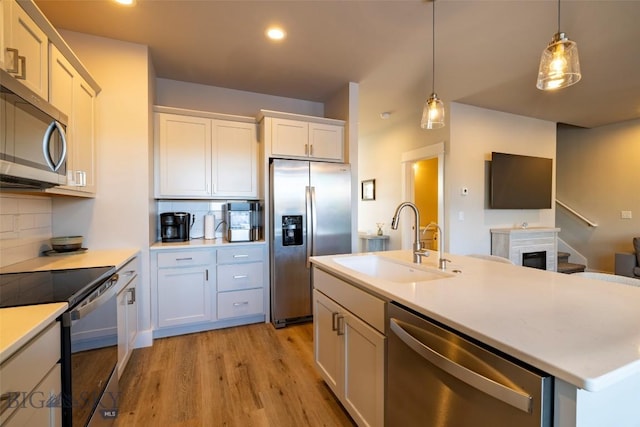 309 Meriwether, Bozeman, MT 59718 - kitchen with decorative backsplash, decorative light fixtures, appliances with stainless steel finishes, a sink, and light wood-style flooring