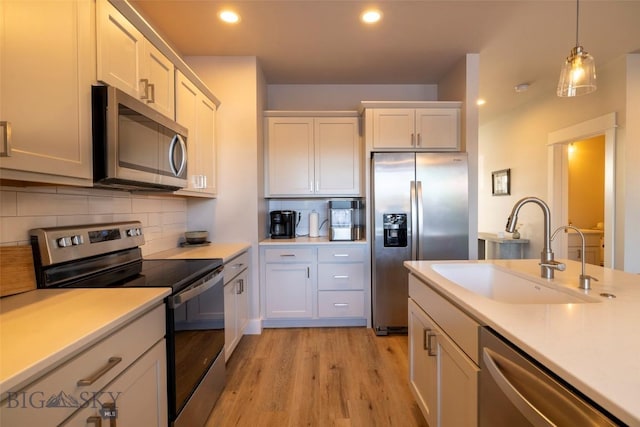 kitchen with a sink, tasteful backsplash, appliances with stainless steel finishes, and light countertops