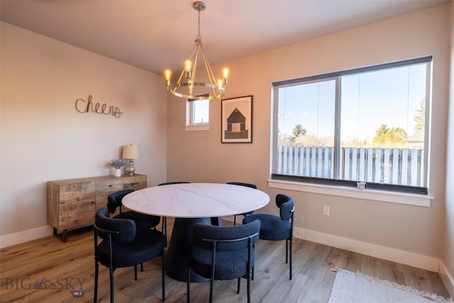 dining room with light wood-type flooring, baseboards, and a notable chandelier