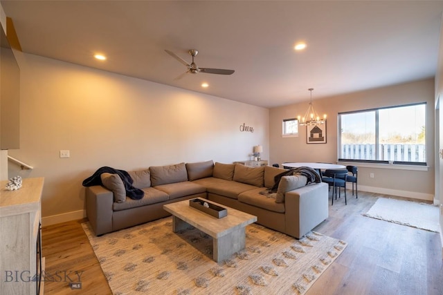 living room with ceiling fan with notable chandelier, light wood-style flooring, recessed lighting, and baseboards