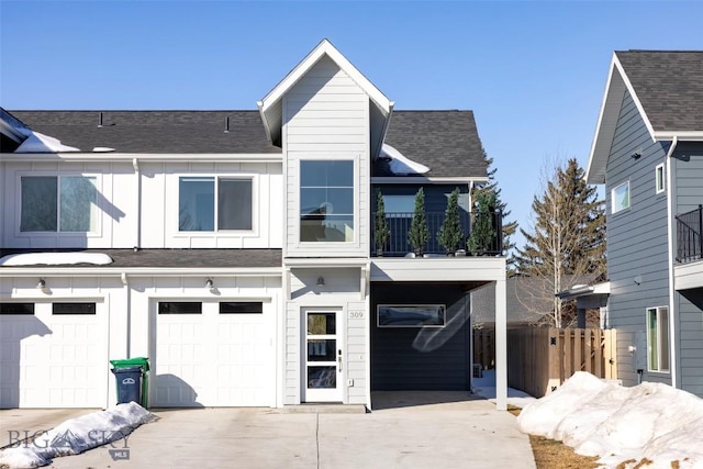 view of front of property featuring a balcony, driveway, roof with shingles, an attached garage, and board and batten siding