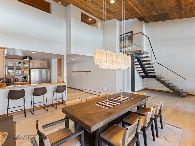 dining space with stairway, wood ceiling, light wood-style flooring, a high ceiling, and a baseboard radiator