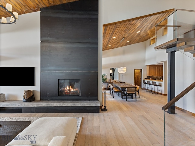 living room featuring high vaulted ceiling, hardwood / wood-style flooring, stairway, an inviting chandelier, and wooden ceiling