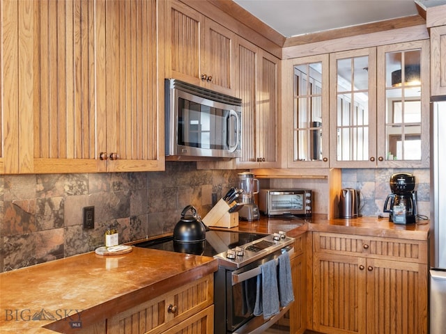 kitchen with stainless steel microwave, a toaster, butcher block countertops, decorative backsplash, and electric range