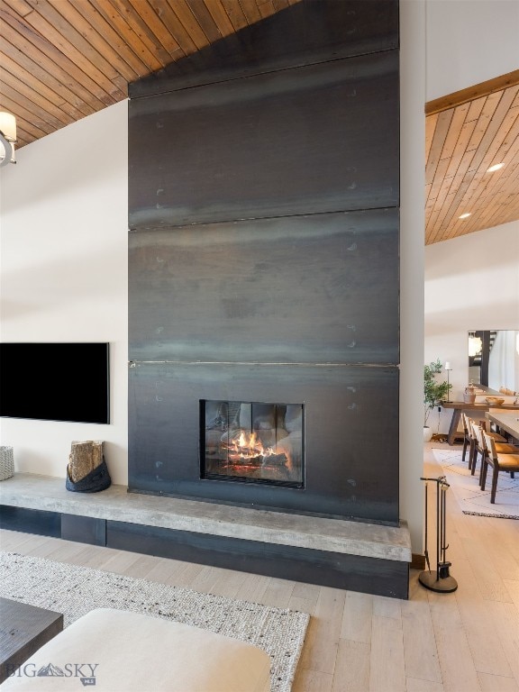 interior details featuring a glass covered fireplace, wooden ceiling, and wood finished floors