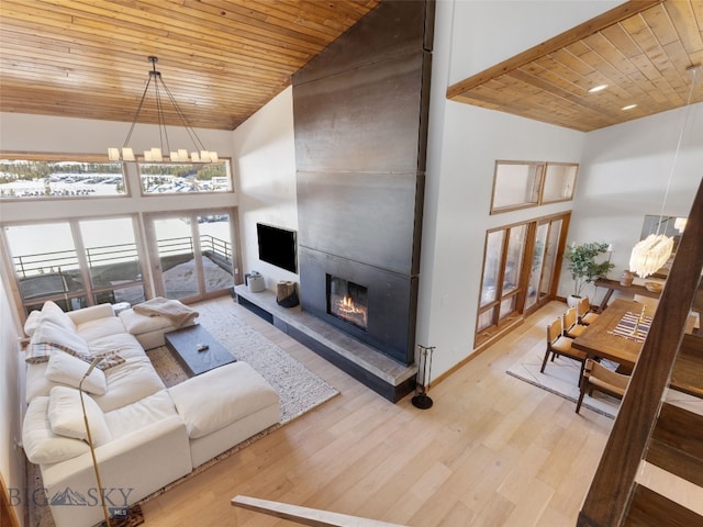 living area featuring an inviting chandelier, wooden ceiling, a fireplace, and high vaulted ceiling