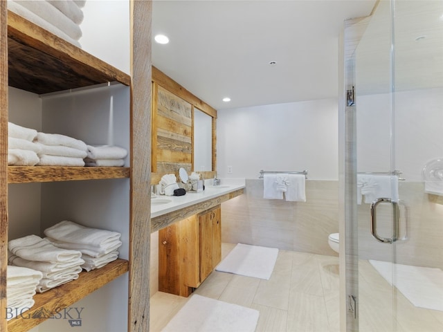 full bath with double vanity, recessed lighting, a stall shower, tile walls, and toilet