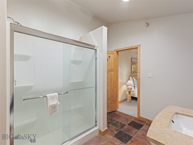 ensuite bathroom with a shower stall, baseboards, stone finish floor, ensuite bath, and a sink