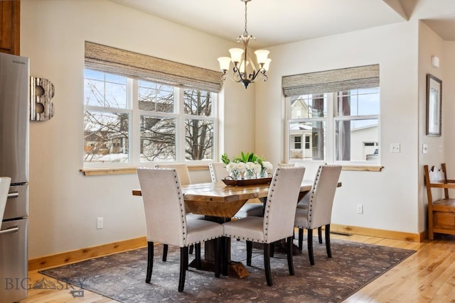 dining space featuring baseboards, an inviting chandelier, and wood finished floors