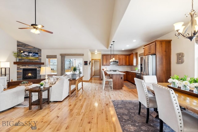 living area featuring high vaulted ceiling, ceiling fan with notable chandelier, recessed lighting, a fireplace, and light wood finished floors