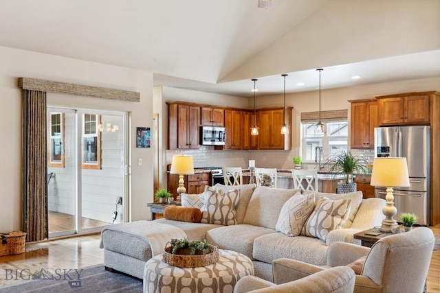 living area with light wood-style flooring, recessed lighting, and high vaulted ceiling