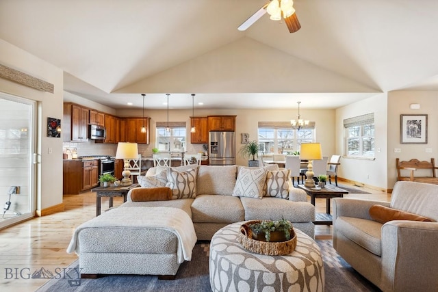 living area with baseboards, light wood-style floors, high vaulted ceiling, and ceiling fan with notable chandelier