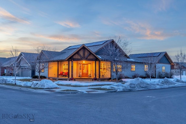 view of front of house with covered porch and roof mounted solar panels