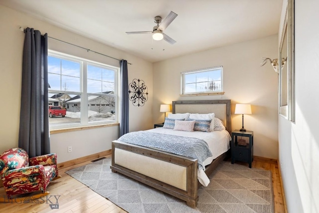 bedroom with visible vents, a ceiling fan, baseboards, and wood finished floors