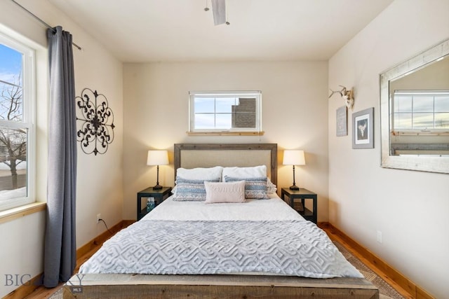 bedroom featuring multiple windows, wood finished floors, and baseboards