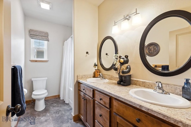 bathroom with a sink, baseboards, toilet, and double vanity