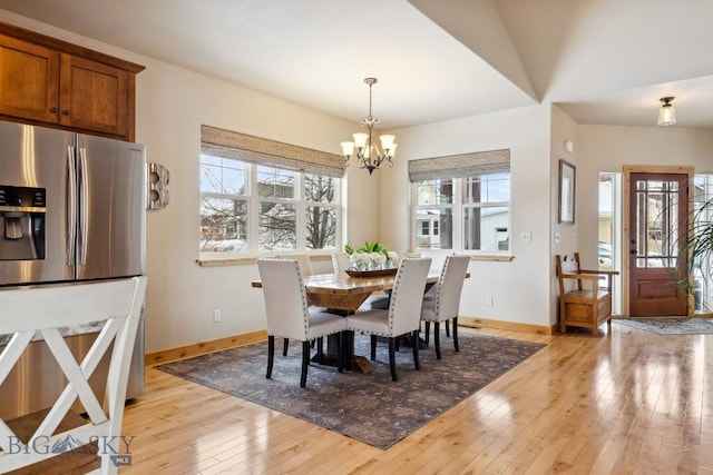 dining room with a notable chandelier, light wood-style floors, and baseboards