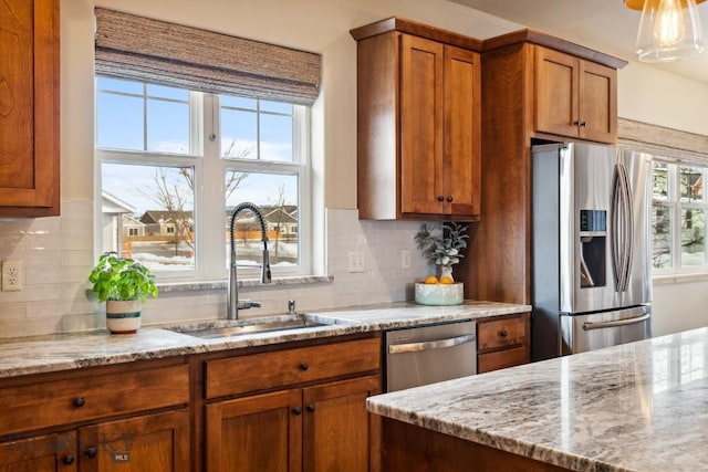 kitchen with decorative backsplash, brown cabinets, appliances with stainless steel finishes, and a sink