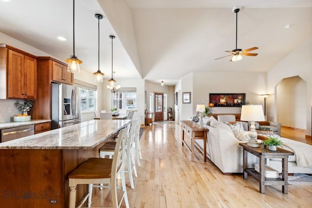 kitchen featuring open floor plan, brown cabinets, stainless steel appliances, and light wood-style flooring