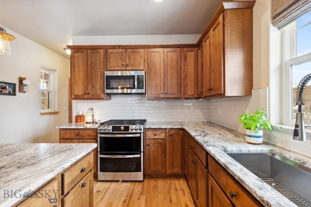 kitchen with a sink, stainless steel appliances, and brown cabinetry