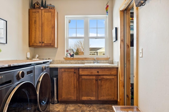 laundry area featuring a sink, stone finish flooring, cabinet space, and washing machine and dryer