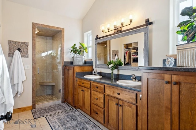 full bath featuring tile patterned floors, double vanity, a stall shower, and a sink