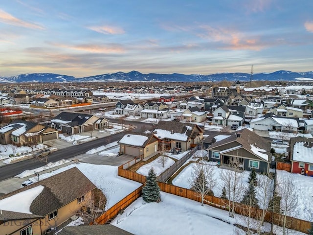 snowy aerial view featuring a mountain view and a residential view