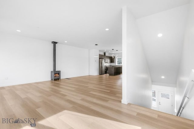 unfurnished living room featuring recessed lighting, light wood-type flooring, and a wood stove