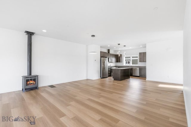 unfurnished living room with recessed lighting, light wood-type flooring, and baseboards